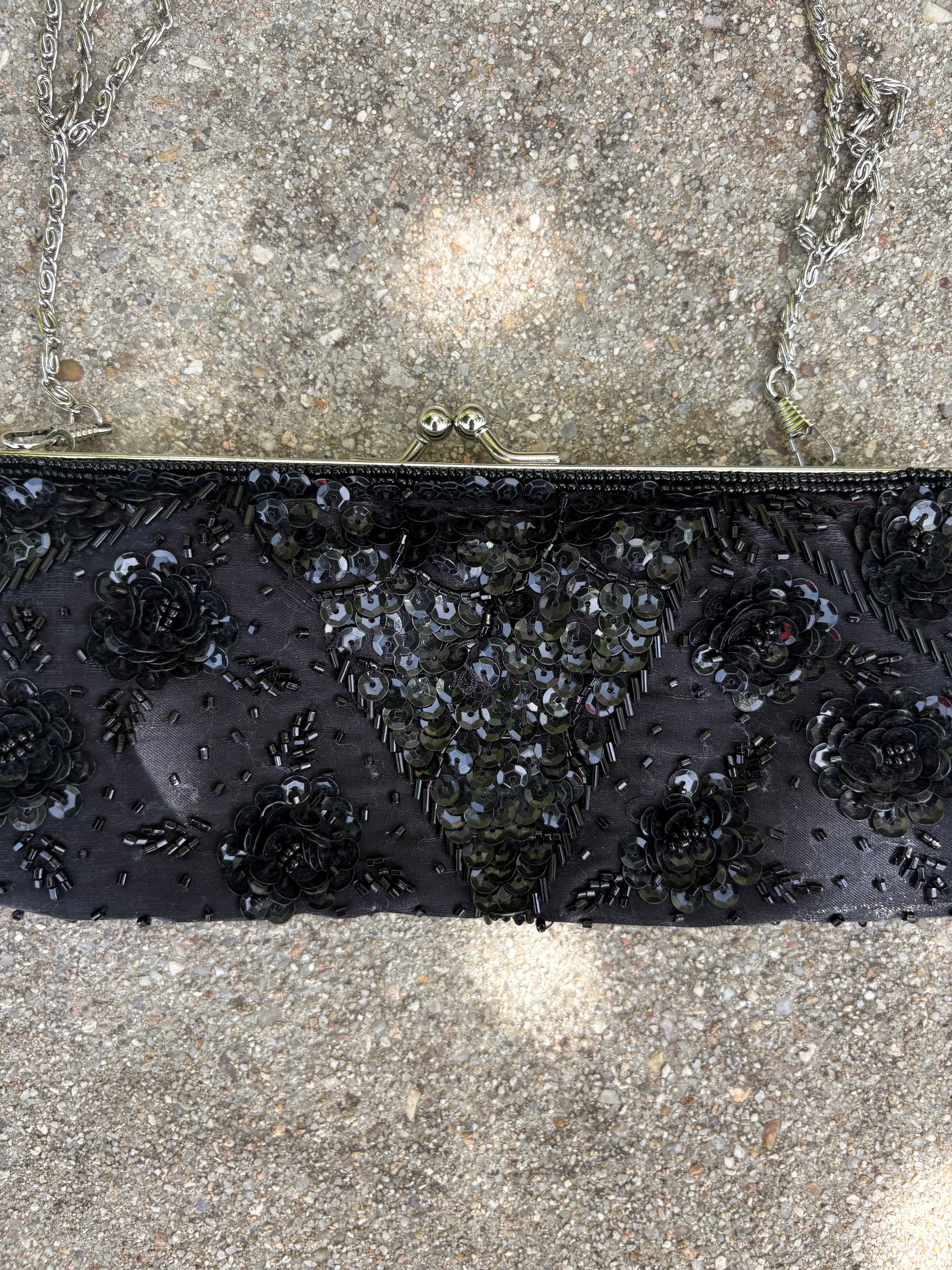 Cartera negra con detalles lentejuela y pedrería flores y cadena metálica plateada