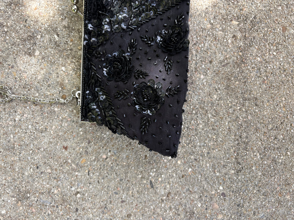 Cartera negra con detalles lentejuela y pedrería flores y cadena metálica plateada