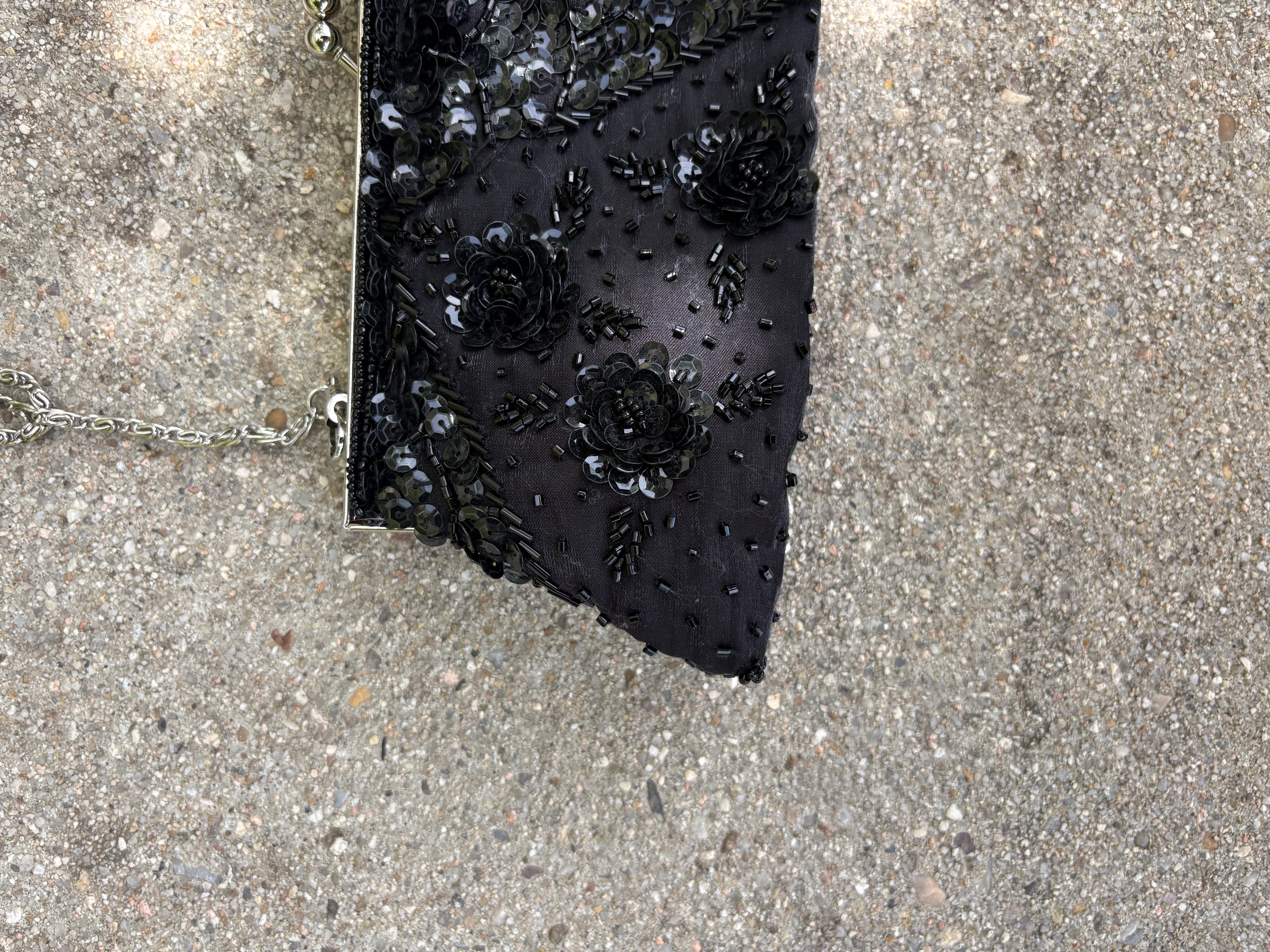 Cartera negra con detalles lentejuela y pedrería flores y cadena metálica plateada