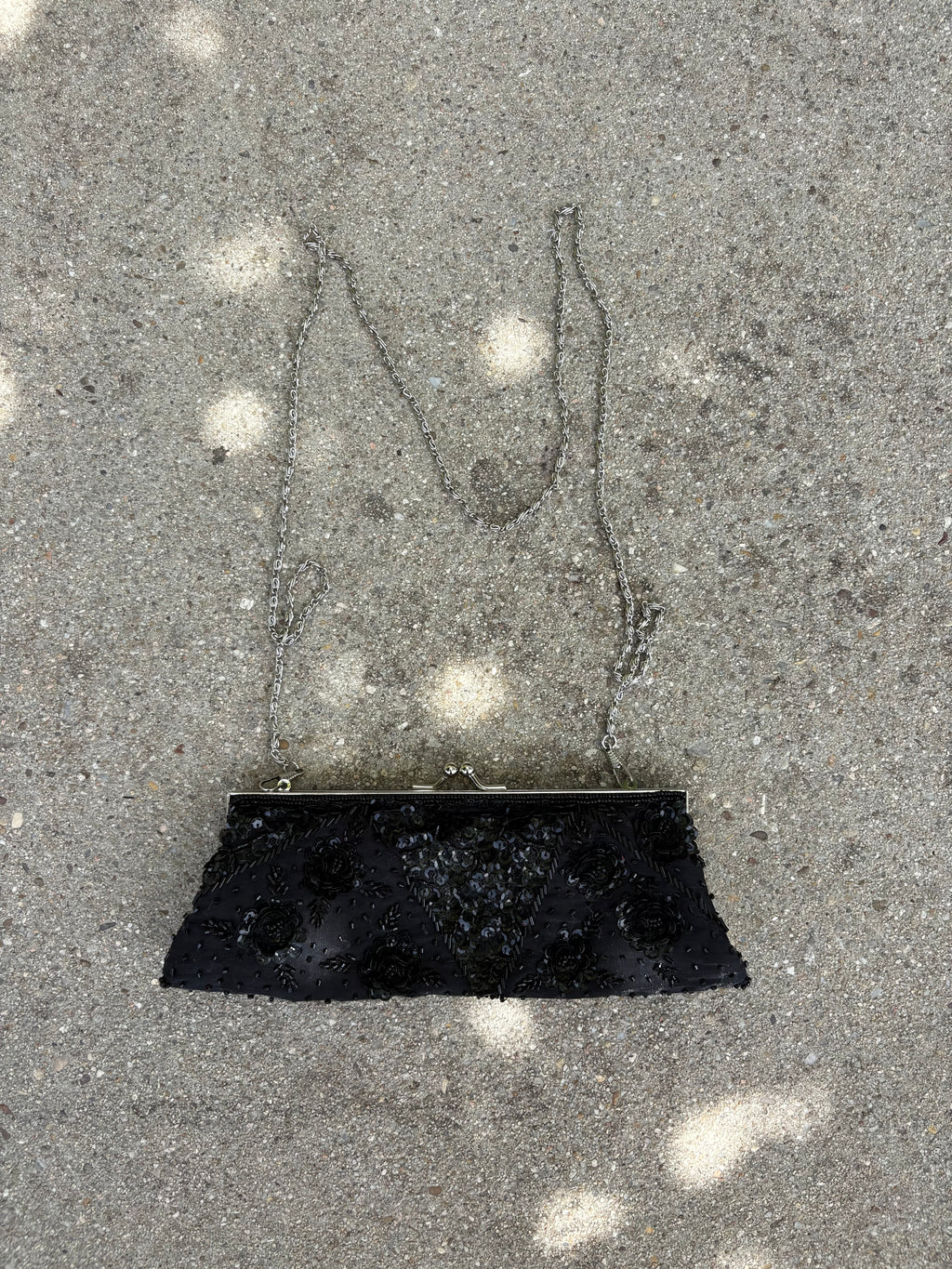 Cartera negra con detalles lentejuela y pedrería flores y cadena metálica plateada
